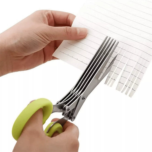 Hand holding a pair of green-handled scissors cutting a piece of paper with a white background